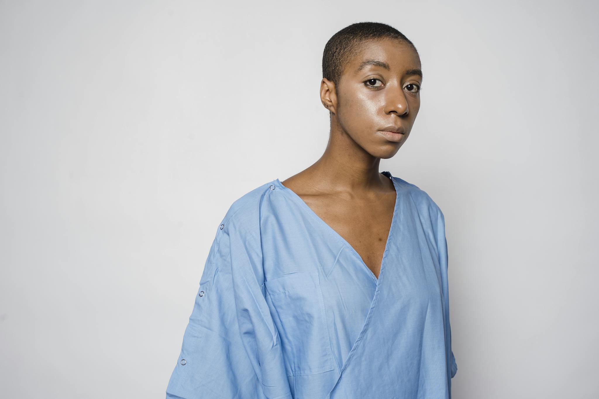 Serious African American female patient with disorder standing against gray background and looking at camera