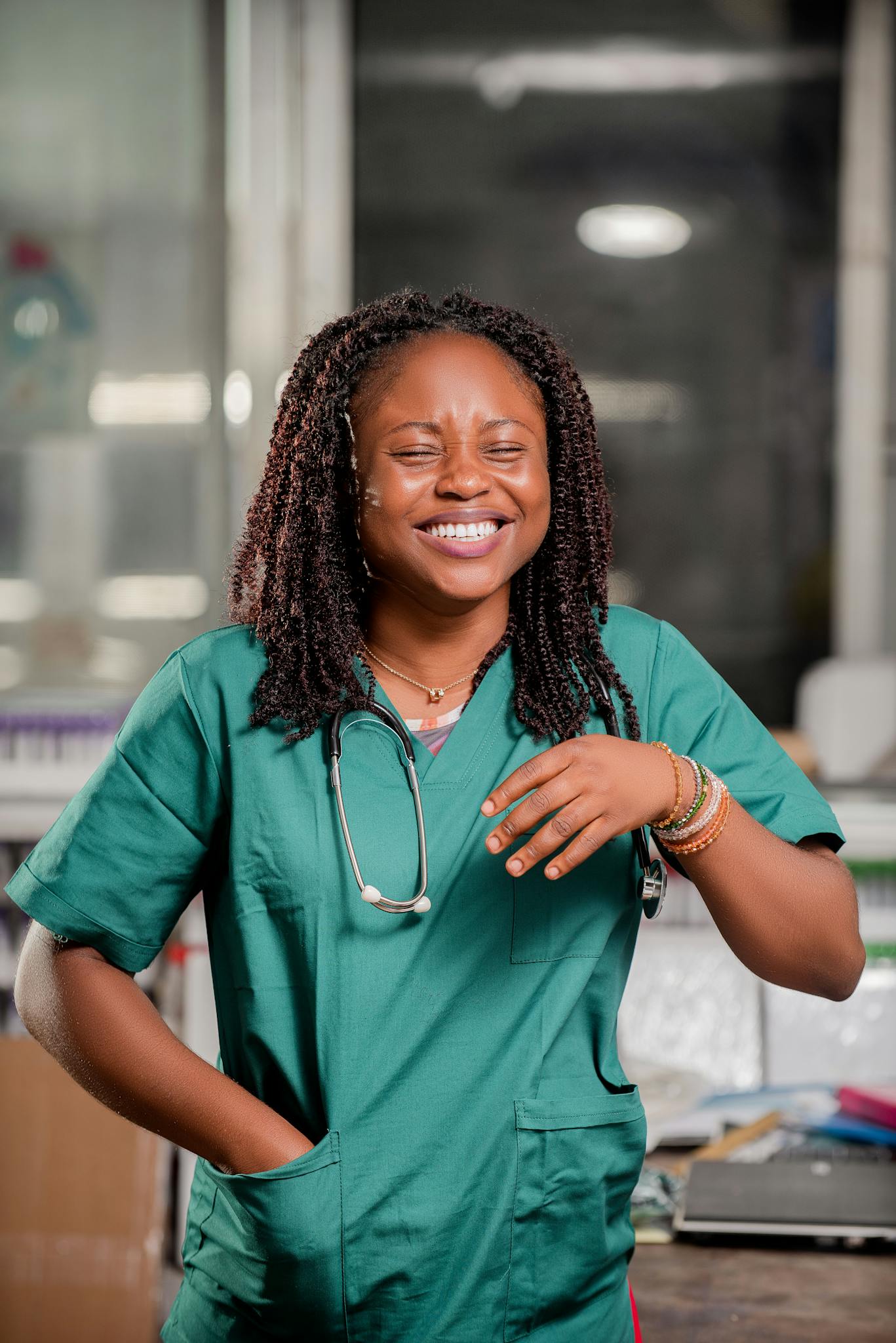 Smiling healthcare worker with stethoscope in a clinic setting, representing positivity and professionalism.