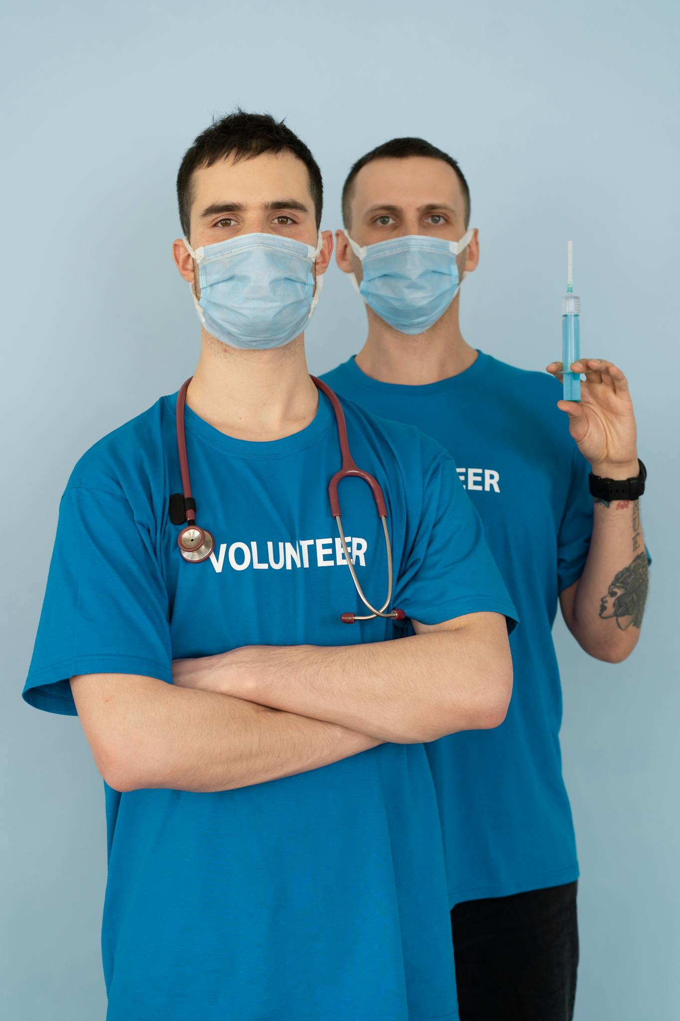 Two healthcare volunteers in masks and uniforms prepared with medical supplies for assistance.